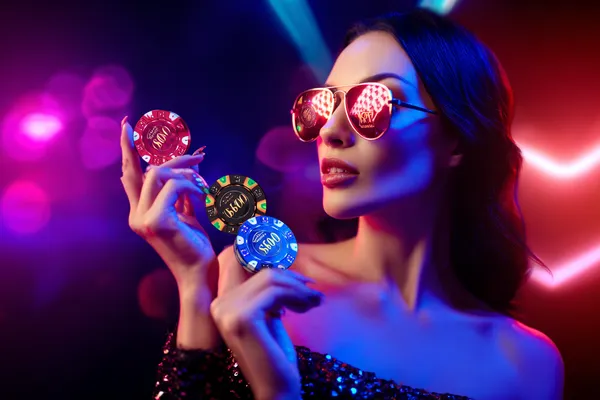 A woman smiling while playing online games on her laptop, surrounded by neon casino elements, showcasing 7555BETT’s diverse game collection.